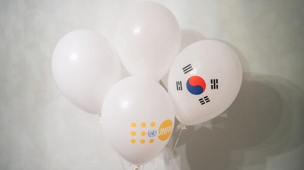 4 White Balloons are in the middle. One balloon is marked with UNFPA logo and One balloon is marked with flag of the republic of Korea.